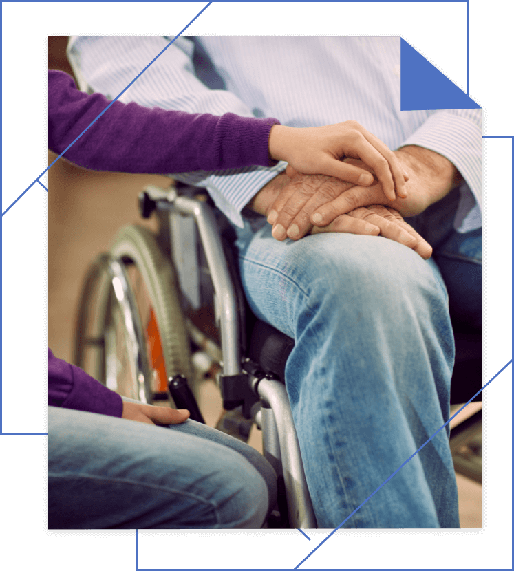 A person in a wheelchair is being comforted by another person who is gently resting their hand on theirs.