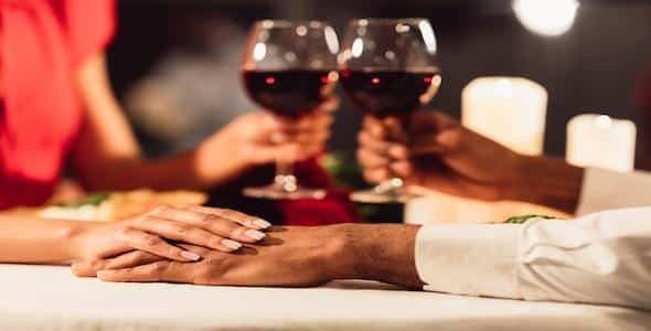 Two people sit at a table, holding hands with wine glasses raised. The scene, reminiscent of romantic dinners shared under the soft glow of candlelight, offers a gentle escape from the chaos of life's metaphorical car collisions.