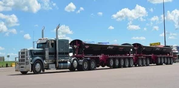 A large semi-truck with multiple trailers is parked on a paved area under a cloudy sky, reminiscent of the fleets that populate the Michigan highways. With 2019 Michigan Commercial Truck Accident Statistics in mind, it’s crucial for consumers to know about road safety and conditions.