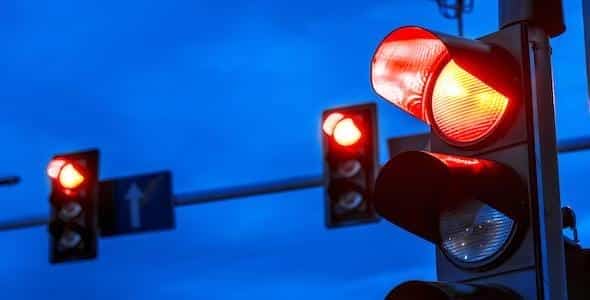 Red traffic lights stand out vividly against the blue sky, highlighting the importance of intersection safety.