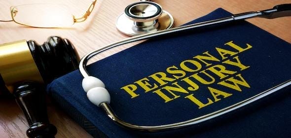 A book titled "Personal Injury Law" rests on a wooden surface, accompanied by a stethoscope, gavel, and glasses, offering insights into avoiding costly mistakes in a personal injury claim.