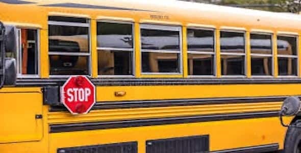 A yellow school bus with an extended stop sign is parked in Sterling Heights, Michigan, emphasizing safety for student loading and unloading. Within the Utica Schools district, stringent measures ensure every aspect of transport avoids the risk posed by a rare drunk bus driver incident.