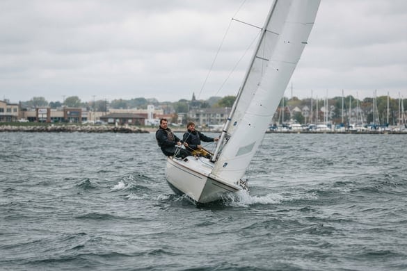 Sailboat heeling sharply in choppy water near a marina, representing boating accidents